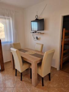 a dining room table with chairs and a television on the wall at Apartments and rooms with parking space Metajna, Pag - 4120 in Metajna