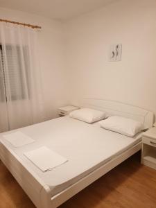 un letto bianco con due cuscini sopra di Apartments and rooms with parking space Metajna, Pag - 4120 a Metajna