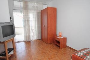 a living room with a television and a wooden floor at Studio Njivice 5458a in Njivice