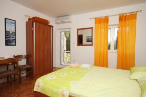 a bedroom with a bed and a window with orange curtains at Studio Drvenik Donja vala 6658a in Drvenik