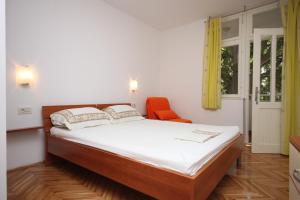 ein Schlafzimmer mit einem Bett und einem orangenen Stuhl in der Unterkunft Apartments by the sea Drvenik Donja vala, Makarska - 6658 in Drvenik