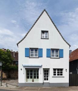 a white house with blue shutters on it at Alte Goldschmiede Südpfalz in Klingenmünster