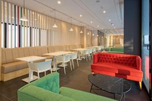 a restaurant with a red couch and tables and chairs at DWO Colours Alcalá in Madrid