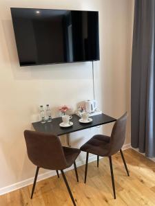 a black table with two chairs and a television on a wall at George Canning Denmark Hill, London in London