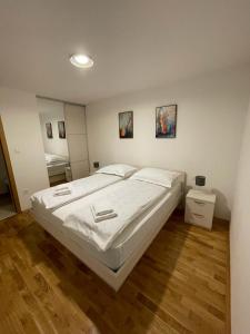 een slaapkamer met een groot wit bed en houten vloeren bij Apartment MV in Čapljina