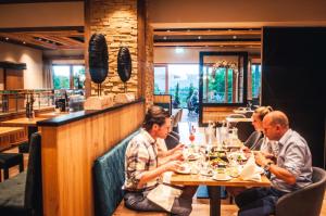 um grupo de pessoas sentadas numa mesa num restaurante em Landhotel Heimathenhof em Heimbuchenthal