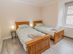 two twin beds in a bedroom with a window at 1 Syme Street in Moffat