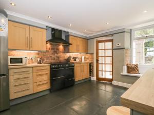 a kitchen with wooden cabinets and black appliances at Roanview Cottage in Askam in Furness