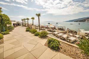 a walkway next to a body of water with palm trees at Noa's Suite in Opatija