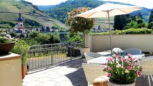 a patio with a table with an umbrella and flowers at Das AMBIENTE I Traumlage - barrierefrei in Zell an der Mosel