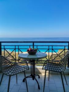 stół z krzesłami i miskę owoców na balkonie w obiekcie Sunset Premium Studio 2 w mieście Agios Nikitas