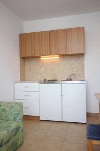 uma cozinha com armários brancos, um lavatório e um sofá em Apartments and rooms by the sea Zaglav, Dugi otok - 8144 em Sali