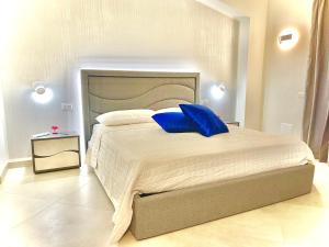 a bedroom with a large bed with blue pillows at Imperial Rooms Tropea in Tropea