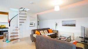 uma sala de estar com um sofá e uma escada em espiral em Stripe Bay em Belmullet