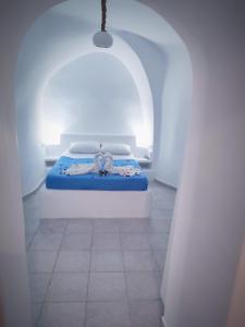 Cama en habitación blanca con colchón azul en EL PATRON SANTORINI en Fira