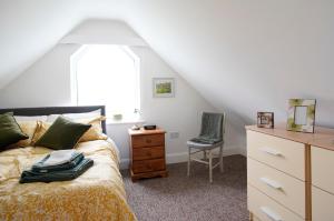 a bedroom with a bed and a chair and a window at Stripe Bay in Belmullet