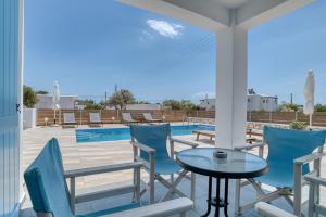 une terrasse avec des chaises, une table et une piscine dans l'établissement Ippocampos Seaside Serenity - Unwind at Paros Poolside Retreats, à Aliki