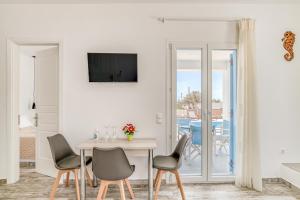 un salon blanc avec une table et des chaises dans l'établissement Ippocampos Seaside Serenity - Unwind at Paros Poolside Retreats, à Aliki