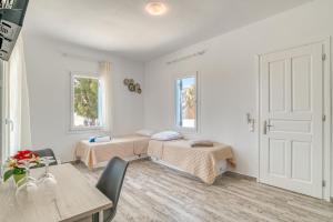 Cette chambre blanche comprend deux lits et une table. dans l'établissement Ippocampos Seaside Serenity - Unwind at Paros Poolside Retreats, à Aliki