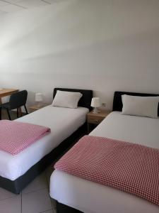 a room with two beds with red and white sheets at Guest House Talas in Osijek