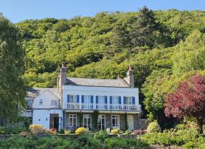 uma grande casa branca com uma varanda numa colina em Borthwnog Hall em Dolgellau