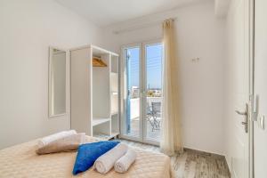 a bedroom with a bed with towels and a balcony at Ippocampos Seaside Serenity - Unwind at Paros Poolside Retreats in Aliki