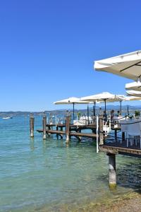 a pier with tables and umbrellas on the water at Hotel Pace in Sirmione