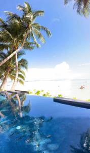 a swimming pool next to a beach with palm trees at Villa Manolo in Ban Bang Makham