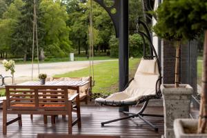 eine Veranda mit einer Schaukel, einem Tisch und Stühlen in der Unterkunft Garda Hotel in Szombathely