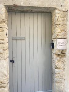 une porte de garage blanche dans un mur en pierre avec un panneau dans l'établissement Bonnieux : Loft - La pause, à Bonnieux