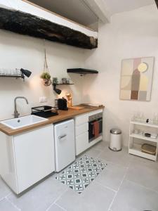 a white kitchen with a sink and a stove at Bonnieux : Loft - La pause in Bonnieux