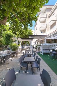 una fila de mesas y sillas frente a un edificio en Mantovani Hotel Murano & Mariù en Rímini