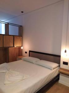 una camera da letto con un grande letto con lenzuola bianche di Apartament Stefani a Sarandë