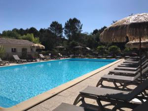 a swimming pool with lounge chairs and umbrellas at Cottage 2 pers KEY WEST Premium in Hourtin