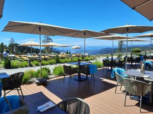 a deck with tables and chairs and umbrellas at DAS ROYAL in Obereggen in Obereggen