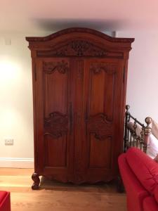 a wooden wardrobe in a room with a red couch at Room in Apartment - Luxury Apartment Lily Suite in Truro
