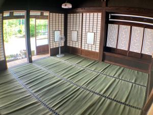 an empty room with a green floor with a fan at ゲストハウス大安吉田 in Matsuzaki