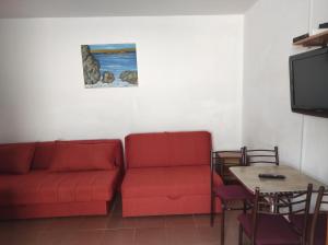 a living room with a red couch and a table at Apartmani Grozdanic Canj in Čanj +126 photos