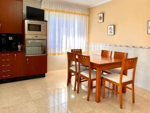 cocina con mesa de madera con sillas y microondas en Casa Sabarís, en Baiona