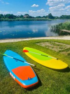 zwei Surfbretter auf dem Gras in der Nähe eines Wasserkörpers in der Unterkunft Eden Resort in Yasnogorodka