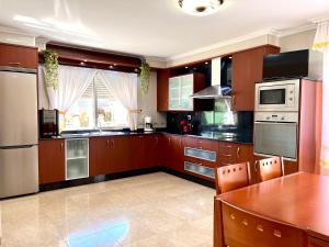 a large kitchen with wooden cabinets and a wooden table at Casa Sabarís in Baiona