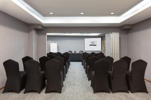 a conference room with black chairs and a screen at Hotel Neo Gading Solo in Solo