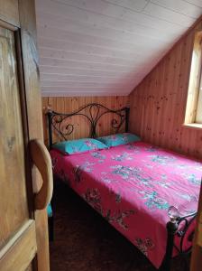 Schlafzimmer mit einem Bett mit einer roten Bettdecke in der Unterkunft Žilių sodyba in Plateliai