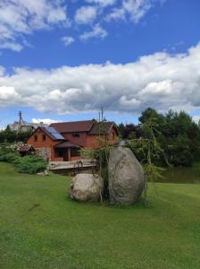 a house with two large rocks in a yard at Žilių sodyba in Plateliai