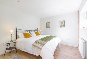 a white bedroom with a large white bed with yellow pillows at La Rose in Gillingham