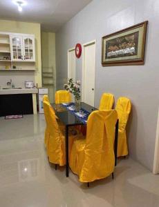 a dining room with a table and yellow chairs at Sunrise Enterprise in Tagum