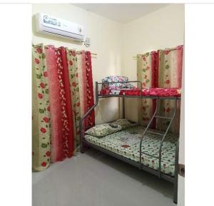 Cette chambre comprend 2 lits superposés avec des rideaux rouges et verts. dans l'établissement Sunrise Enterprise, à Tagum