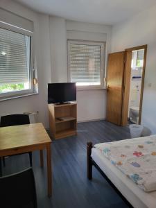 a bedroom with a bed and a table and a tv at Guest House Talas in Osijek