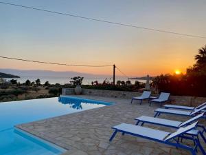 a pool with chairs and a sunset in the background at Casa Marimar Boutique Bungalows & Suites in Porto Heli