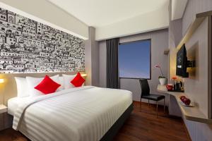 a hotel room with a bed with red pillows at Hotel Neo Gading Solo in Solo